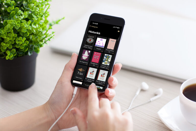 Hender som holder en mobiltelefon som viser Tibi-appen. Fotografi.