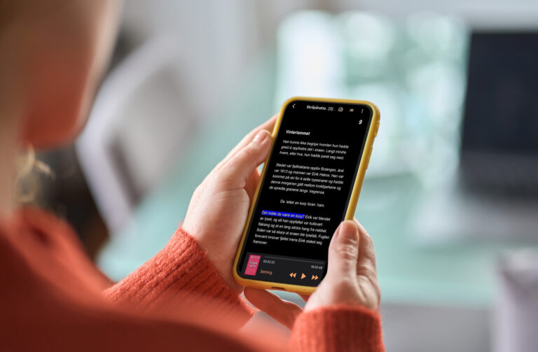 Hender holder en mobil med Tibi-appen.
